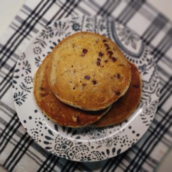 close up of chocolate chip pancakes on a white and blue plate