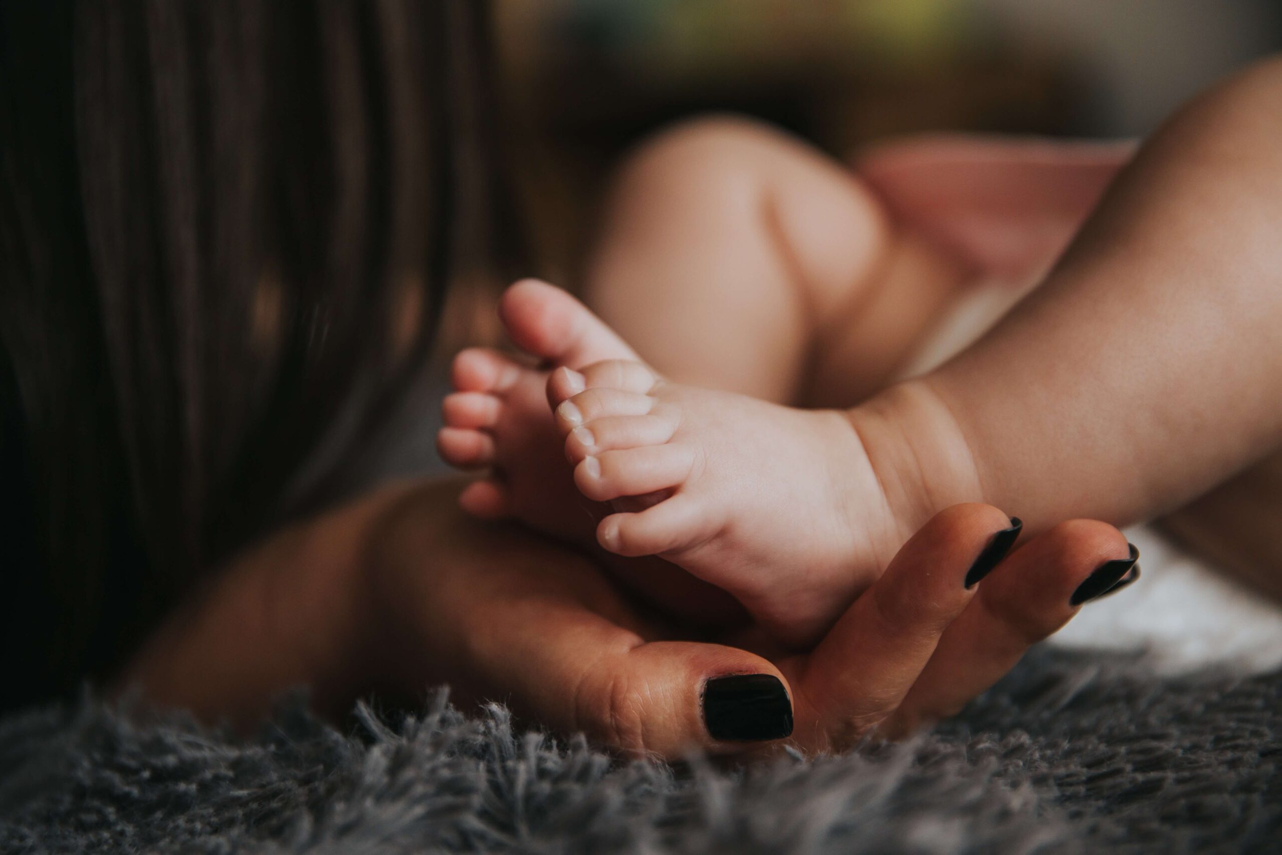 close-up, women cradling baby's feet in hands