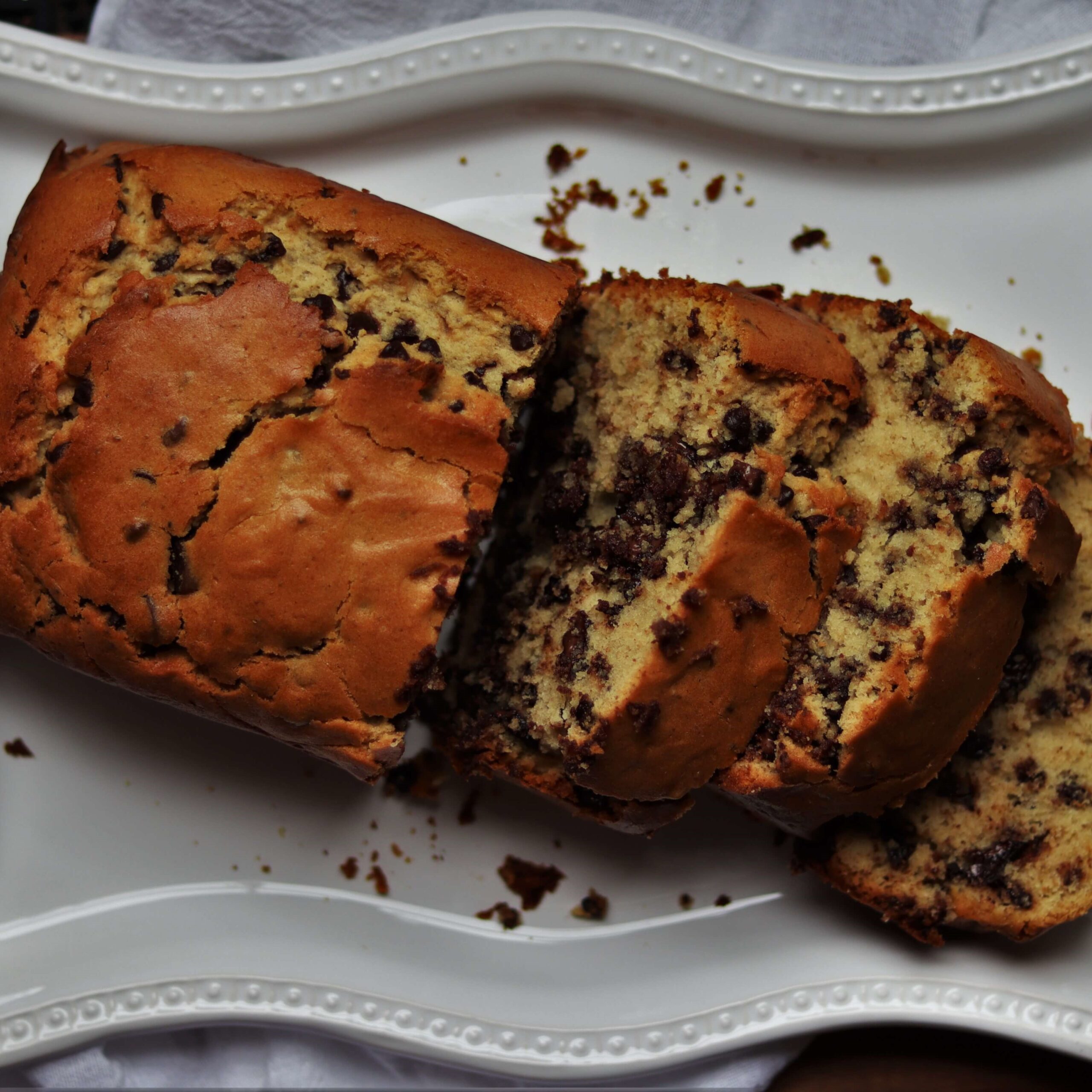 close up of cooked and sliced chocolate chip bread on a white serving tray