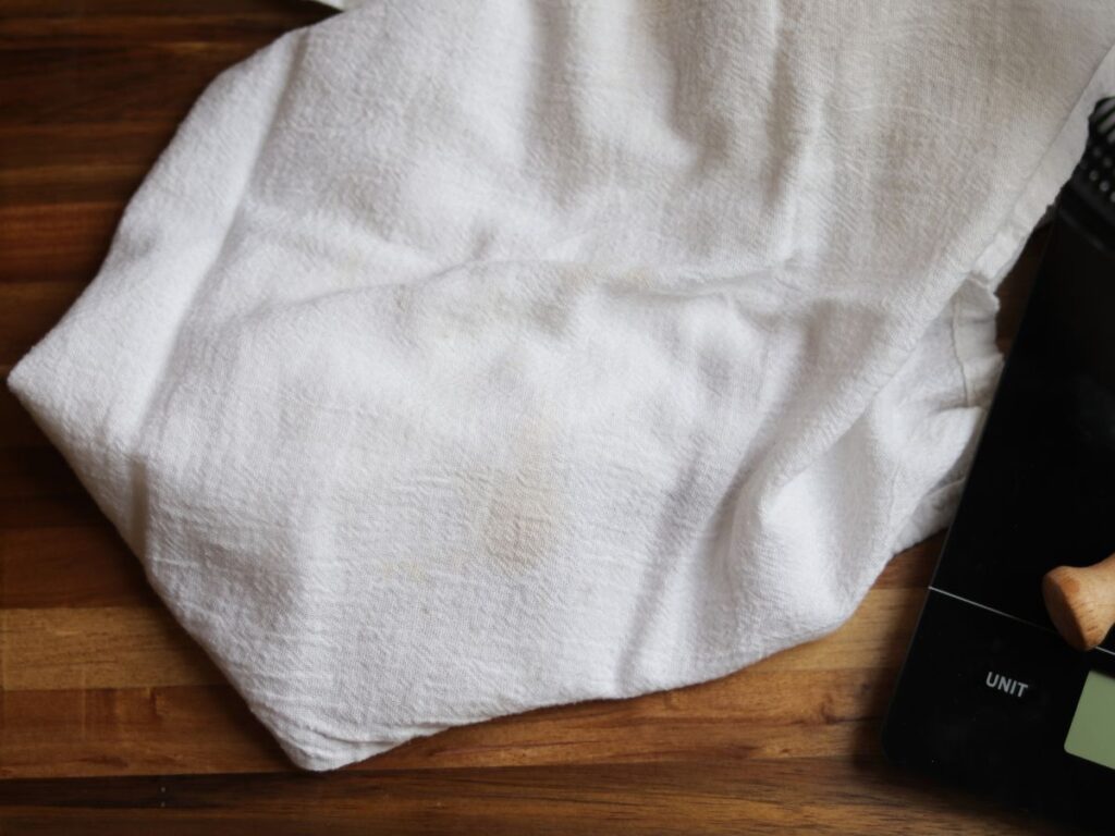 white teal towel on a wooden cutting board next to a glass kitchen scale