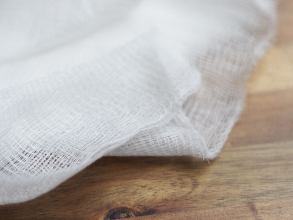up close image of cheese cloth on a wooden cutting board