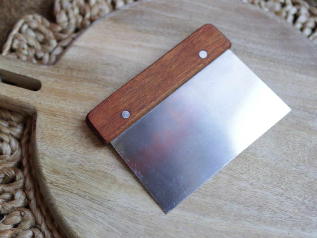 bench scraper on a wooden cutting board