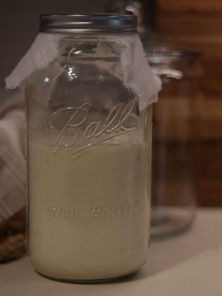 glass mason jar full of sourdough starter on a kitchen counter